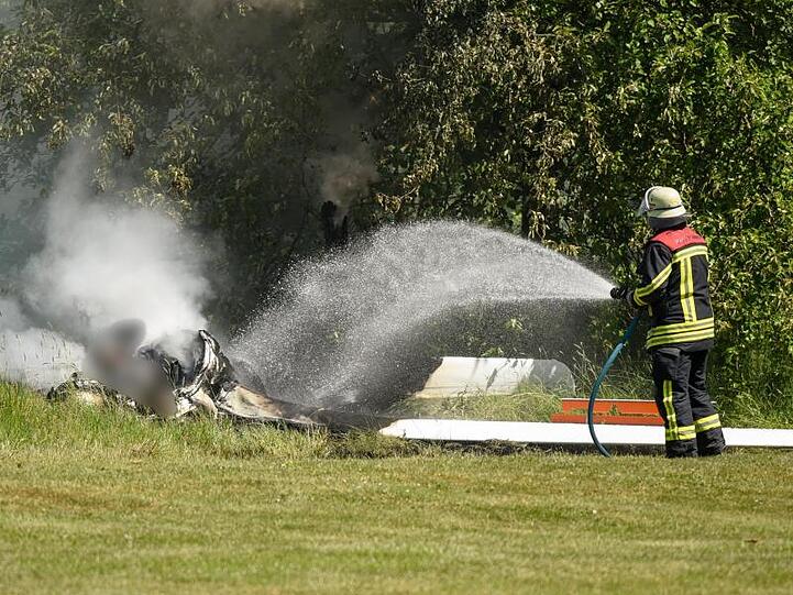 Ein Feuerwehrmann löscht an der Absturzstelle die letzten Glutreste.