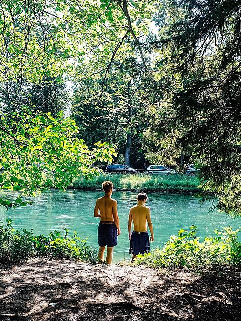 Zwei Burschen haben sich ein ruhiges Platzerl am Isarwerkkanal bei Thalkirchen gesichert und ihre Handtücher ausgebreitet. Langsam tasten sie sich ins kalte Wasser – bei der Hitze fällt das Eintauchen in die Isar besonders schwer. Ein paar Meter weiter scheint die Kälte schon vergessen: Eine Gruppe junger Buben schwingt an einem Seil in den Kanal und hat dabei eine heiden Gaudi.