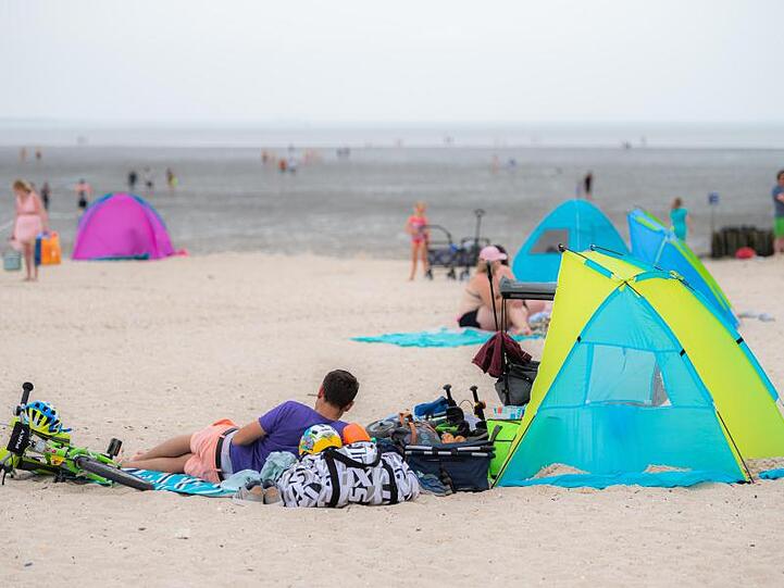 Touristen entspannen am Badestrand von Schillig in Niedersachsen.
