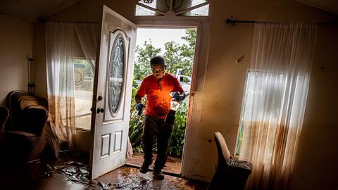 Glenn Duquez, stellvertretender Pastor der Church of God Jesus is Alive Fellowship, tr&auml;gt eine Lampe in das schlammdurchtr&auml;nkte Kirchengeb&auml;ude, um nach der Flut aufzur&auml;umen.