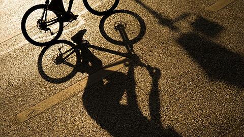 Der Schatten eines Radfahrers auf einer Straße in der Münchner Innenstadt.