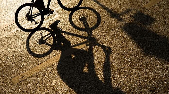 Der Schatten eines Radfahrers auf einer Straße in der Münchner Innenstadt.