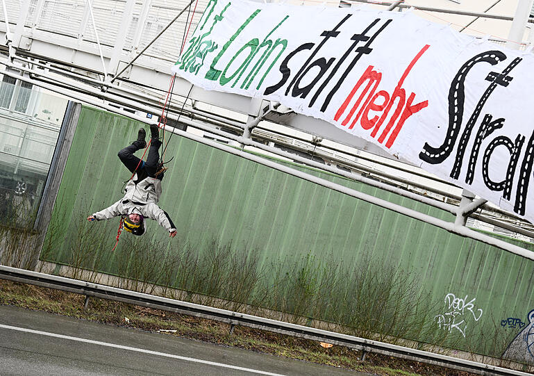 Eine Demonstrationsteilnehmerin hat sich über die in beide Richtungen gesperrten Autobahn A9 von einer Fußgängerbrücke abgeseilt.
