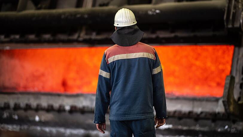 Ein Arbeiter steht vor einem Schmelzofen mit heißen flüssigen Aluminium. (Symbolbild)