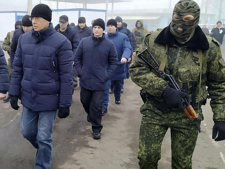 Ein Separatistensoldat begleitet ukrainische Kriegsgefangene zum Kontrollpunkt.