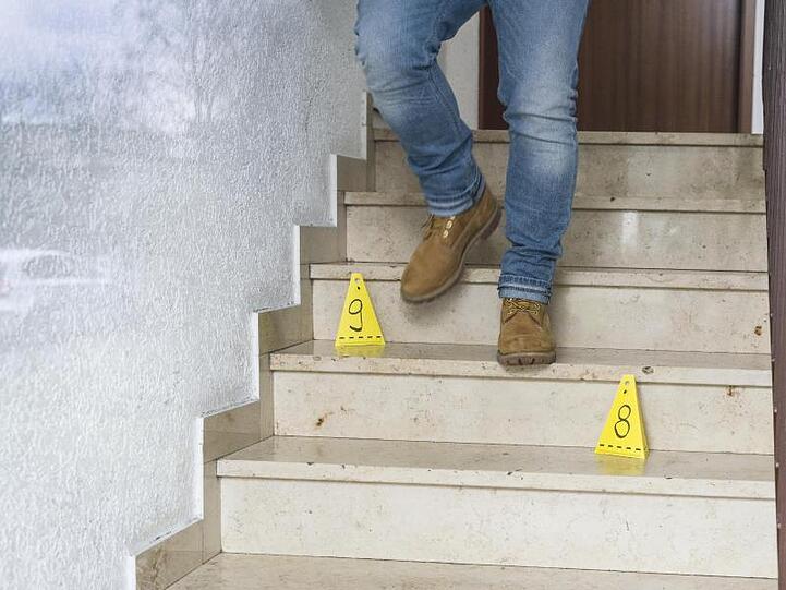 Ein Polizeibeamter geht an Markierungen der Spurensicherung am Tatort vorbei.