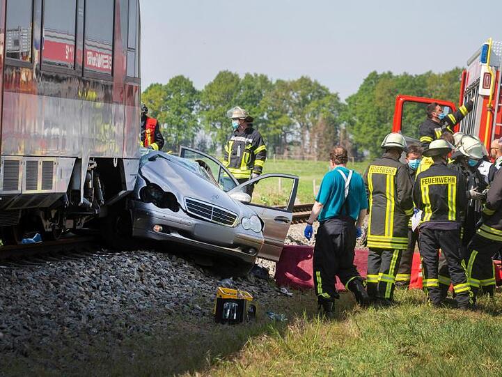 Rettungskräfte stehen an der Unfallstelle. Das Auto wurde von dem Zug etwa 50 Meter mitgeschleift.