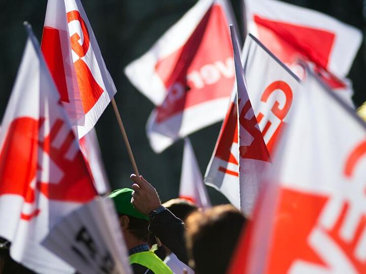 Teilnehmer eines Warnstreiks im öffentlichen Dienst schwenken Gewerkschaftsfahnen von GEW und Verdi.