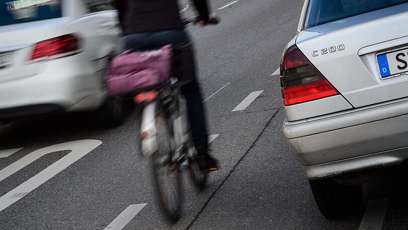 Zwischen der Autofahrbahn und geparkten Wagen ist für eine Radfahrerin nur wenig Platz. Ist es Zufall, dass sich Schlagzeilen über Aggression und Rücksichtslosigkeit im Straßenverkehr häufen?