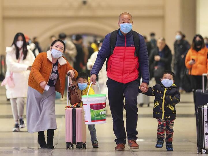 Reisende mit Atemschutzmasken gehen durch den Bahnhof Hankou in der chinesischen Stadt Wuhan.