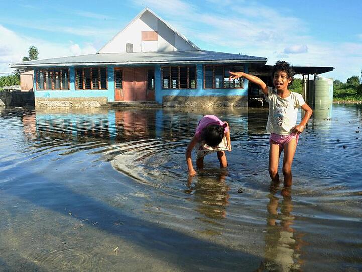 Kinder spielen auf einem vom Meerwasser überfluteten Platz in Funafuti, der Hauptstadt des pazifischen Inselstaats Tuvalu.