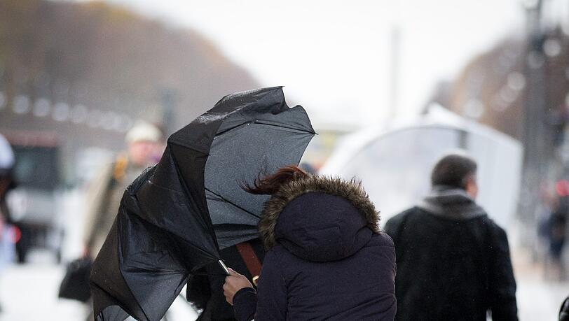 Eine Passantin kämpft mit dem Wind um ihren Regenschirm. Eine Passantin kämpft mit dem Wind um ihren Regenschirm.