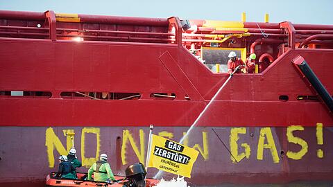 Greenpeace-Aktivisten mit einem Schlauchboot vor einem Schiff im Hafen von Mukran.