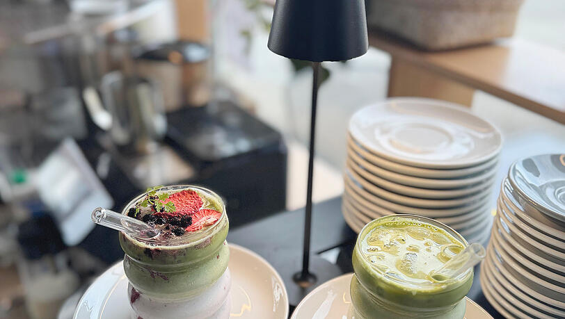 Links: ein Matcha Latte mit Beeren-Mix-Topping, daneben ein Matcha Latte. Links: ein Matcha Latte mit Beeren-Mix-Topping, daneben ein Matcha Latte.