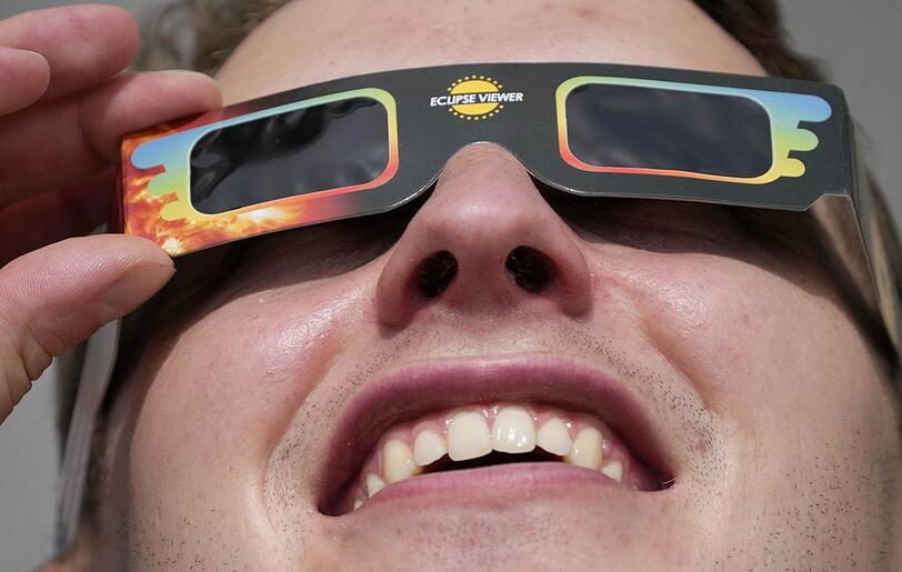 Ein Mann trägt eine Spezialbrille, um eine partielle Sonnenfinsternis zu beobachten.