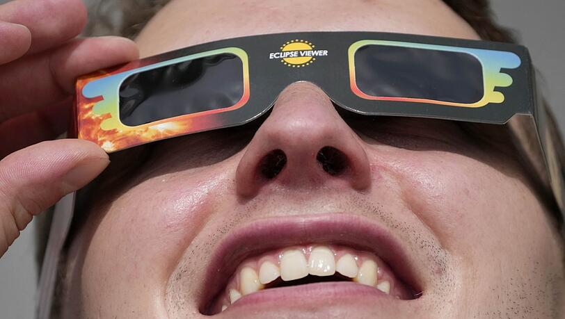 Ein Mann trägt eine Spezialbrille, um eine partielle Sonnenfinsternis zu beobachten.