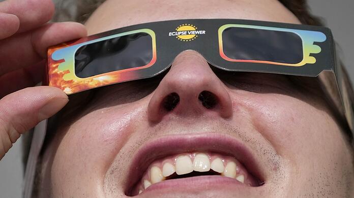 Ein Mann trägt eine Spezialbrille, um eine partielle Sonnenfinsternis zu beobachten.