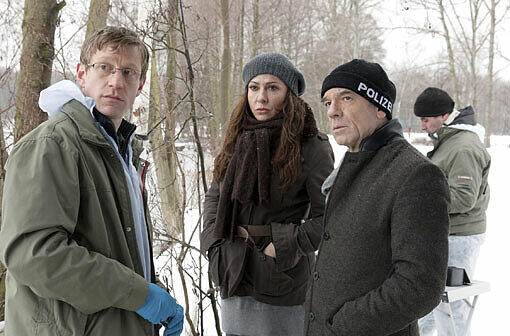 Kriminaltechniker Wolfgang Menzel (Maxim Mehmet, links) unterrichtet die Hauptkommissare Eva Saalfeld (Simone Thomalla) und Andreas Keppler (Martin Wuttke) über die ersten Erkenntnisse am Tatort. Die siebenjährige Amelie ist tot in einem Boot am See aufgefunden worden.