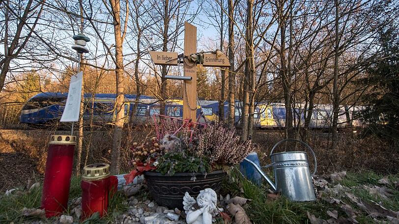 Ein Holzkreuz mit der Aufschrift "In lieber Erinnerung - 09.02.2016" und ein paar Grablichter stehen an der Bahnstrecke zwischen Bad Aibling und Rosenheim.