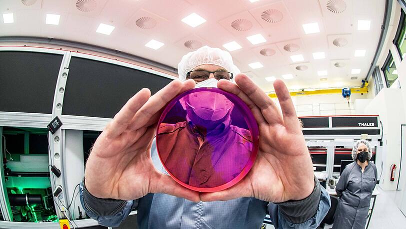 Ein Wissenschaftler zeigt eine Laserlinse. Die LMU arbeitet eng mit der M&uuml;nchner Firma Marvel Fusion zusammen, die eine laserbasierte Kernfusion entwickelt.