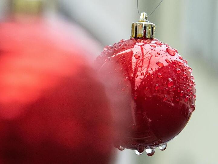 Nasse Christbaumkugeln hängen nach einem Regen an einem Baum. Foto: Sebastian Gollnow/dpa