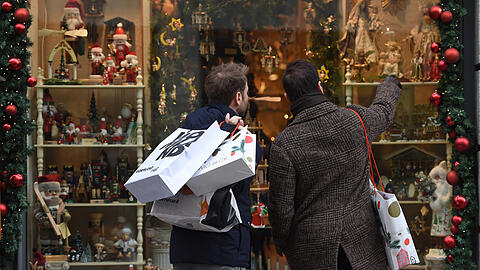 Rückblick: Einkäufer vor einem weihnachtlich dekorierten Schaufenster in München - ob die Tüten heuer auch so schnell gefüllt sind?