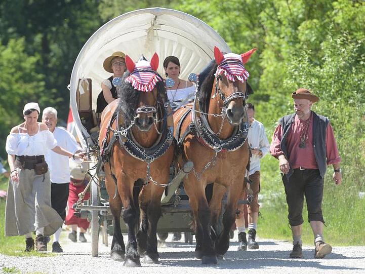 Kostümierte Menschen begleiten einen Planwagen. Es wird ein Handelszug aus dem 18. Jahrhundert nachgestellt.