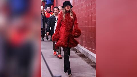 Taylor Swift in rotem Fellmantel bei einem NFL-Spiel.