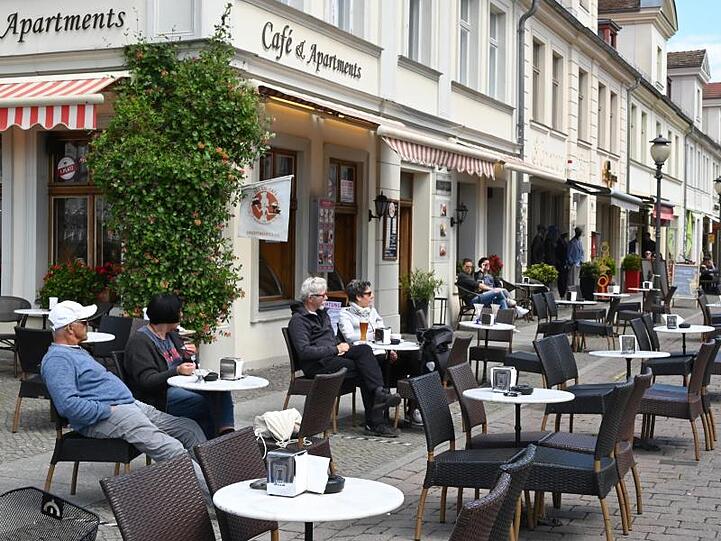 Trotz strahlender Sonne sind die meisten Plätze vor einer Gaststätte an der Brandenburger Straße in Potsdam leer. Ab Montag treten im Gastgewerbe weitere Lockerungen in Kraft.