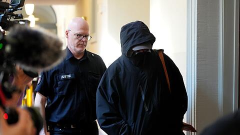 Ein Angeklagter wird von einem Polizisten zum Gerichtssaal begleitet.