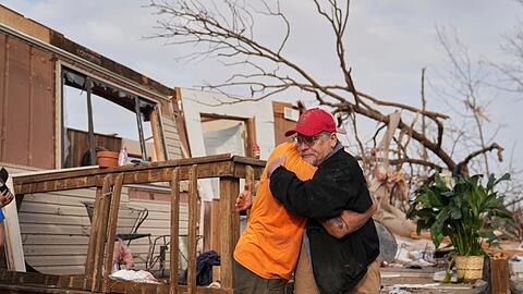 Nach dem Durchzug eines Tornados in Missouri spenden sich Freunde Trost und räumen auf.