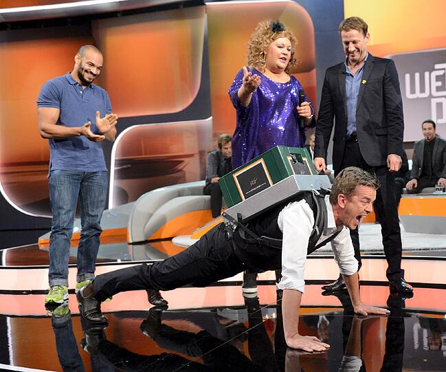 Die Gäste amüsieren sich prächtig, während Markus Lanz sich mit dem Bierkasten auf dem Rücken abmüht.