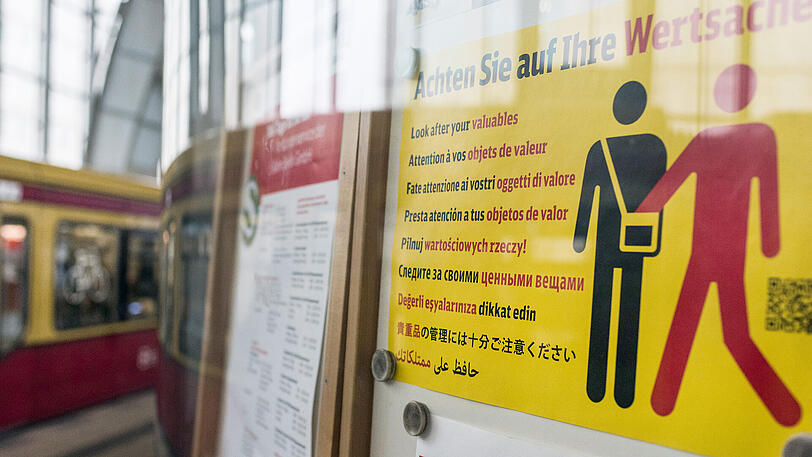 Ein Hinweisplakat warnt auf dem Bahnhof Alexanderplatz in Berlin in mehreren Sprachen vor Taschendiebstahl.