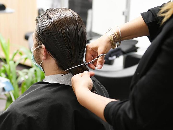 Dem Passionsdarsteller Samuel Kloiber werden die langen Haare von Friseurmeisterin Katharina Daisenberger wieder abgeschnitten. Foto: Angelika Warmuth/dpa