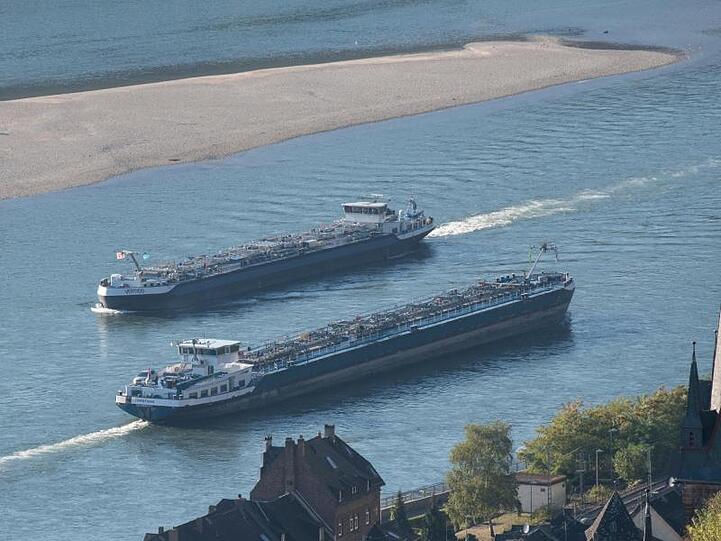 Zwei Tankschiffe fahren durch die stark verengte Fahrrinne des Rheins, während das extreme Niedrigwasser des Flusses eine große Sandbank (im Hintergrund) freigelegt hat.