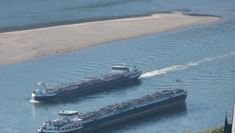 Zwei Tankschiffe fahren durch die stark verengte Fahrrinne des Rheins, während das extreme Niedrigwasser des Flusses eine große Sandbank (im Hintergrund) freigelegt hat. Zwei Tankschiffe fahren durch die stark verengte Fahrrinne des Rheins, während das extreme Niedrigwasser des Flusses eine große Sandbank (im Hintergrund) freigelegt hat.