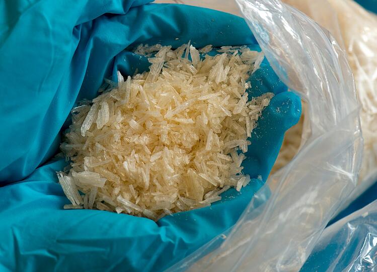 Mit Gummihandschuhen geschützt hält ein Polizeiermittler sichergestelltes Crystal Meth in den Händen. Die Substanz sieht
so harmlos aus wie Kandiszucker, wird aber mittlerweile als gefährlichste Droge der Welt eingestuft.
