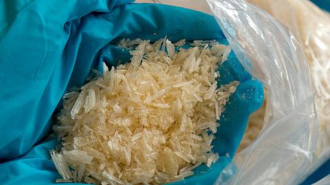 Mit Gummihandschuhen geschützt hält ein Polizeiermittler sichergestelltes Crystal Meth in den Händen. Die Substanz sieht
so harmlos aus wie Kandiszucker, wird aber mittlerweile als gefährlichste Droge der Welt eingestuft.