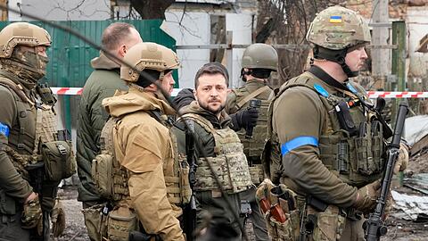 Wolodymyr Selenskyj (M), Präsident der Ukraine, begutachtet den Schauplatz eines Gefechts in Butscha.