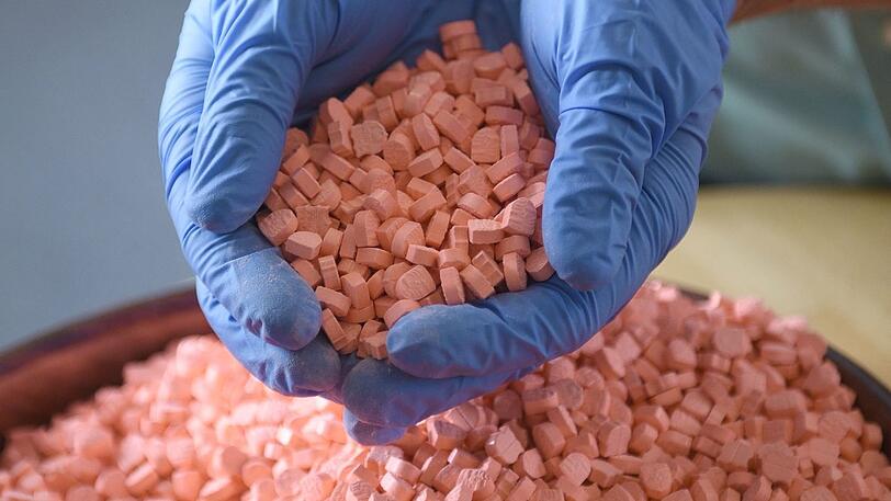 Ein Zollmitarbeiter zeigt Ecstasy-Pillen.