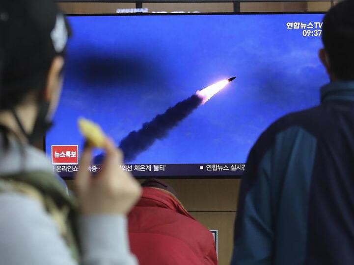 Menschen im Bahnhof von Seoul verfolgen eine Nachrichtensendung, in der über den Abschuss der Raketen berichtet wird.