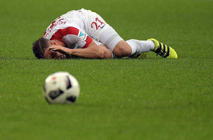 Nach dem brutalen Foul liegt Augsburgs Dominik Kohr mit schmerzverzerrtem Gesicht am Boden.