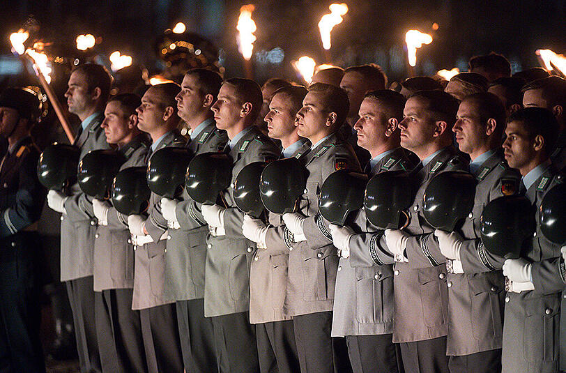Zahlreiche Soldaten stehen bei einem Großen Zapfenstreich vor dem Reichstagsgebäude in Berlin.
