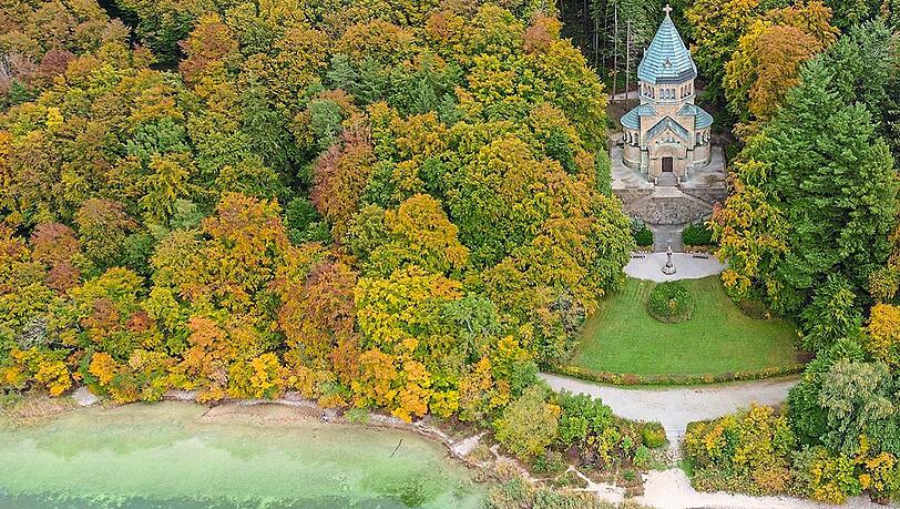 Die Votivkapelle zum Gedenken an den Kini in Berg, umgeben von Natur. Am Ufer davor ist das Kreuz für Ludwig II. zu erkennen. Die Votivkapelle zum Gedenken an den Kini in Berg, umgeben von Natur. Am Ufer davor ist das Kreuz für Ludwig II. zu erkennen.