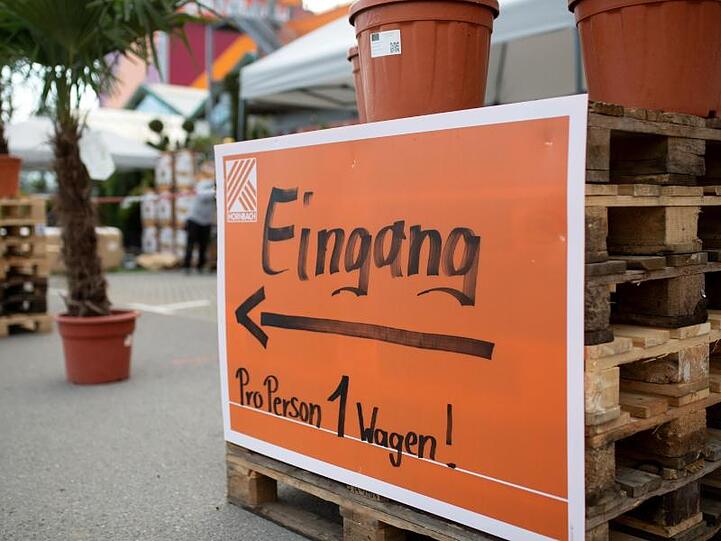 Ein Schild mit der Aufschrift "Eingang - Pro Person 1 Wagen!" am Eingang eines Baumarkts.