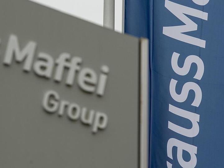 Das Logo der "KraussMaffei Group" ist an einem Eingang zum Werksgelände in Allach bei München (Bayern) auf einer Fahne zu sehen. Foto: picture alliance / dpa/Archivbild