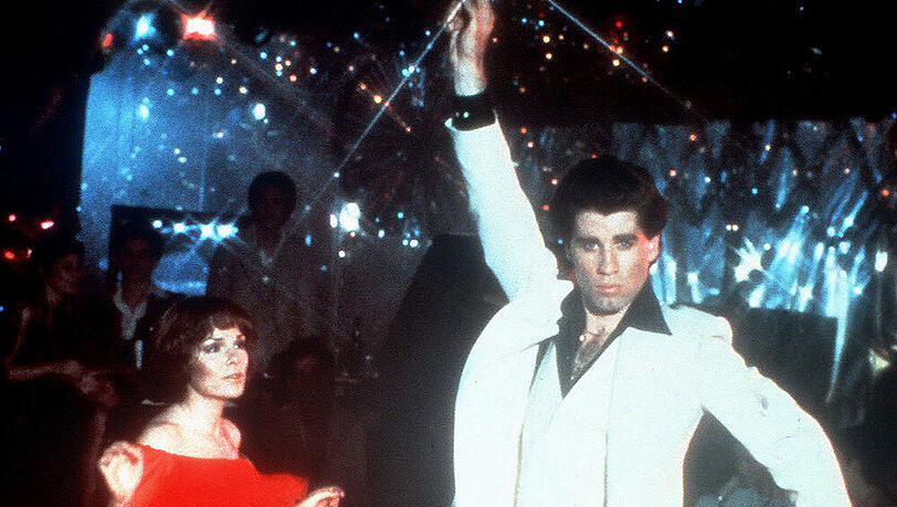 Wenn er in der Disco auf der Tanzfläche seine Show abzieht, liegen ihm die Mädchen zu Füßen: John Travolta als Tony Manero mit Karen Lynn Gorney als Silvia Wenn er in der Disco auf der Tanzfläche seine Show abzieht, liegen ihm die Mädchen zu Füßen: John Travolta als Tony Manero mit Karen Lynn Gorney als Silvia
