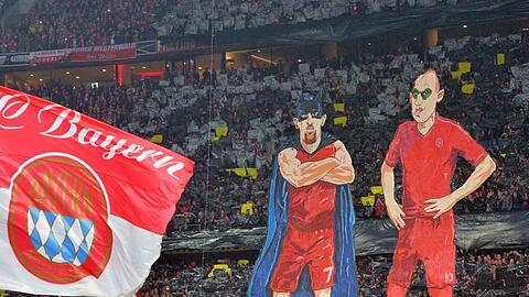 Franck Ribery als "Batman" (l) und Arjen Robben als "Robin" als überdimensionale Figuren vor dem Fanblock des FC Bayern München. Foto: Peter Kneffel/Archivbild