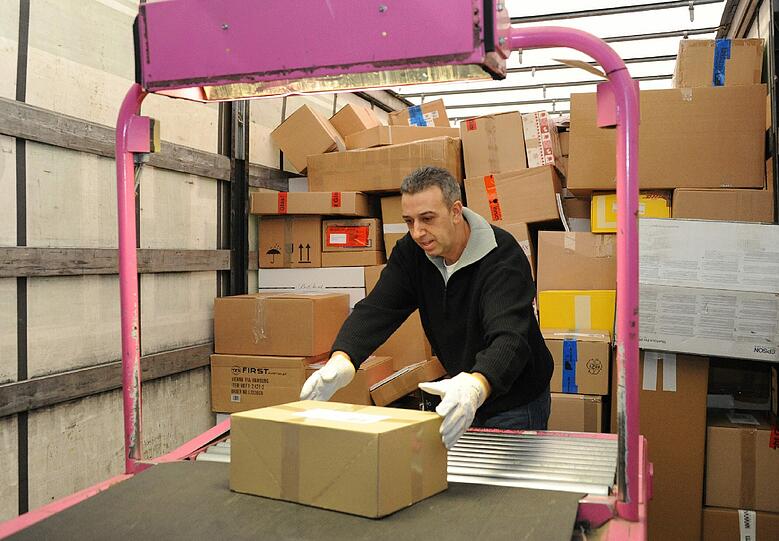 Die Fahrt auf den Laufbändern endet für Pakete in die Republik auf einem pink gerahmten Förderband, auf das sie über eine türkisfarbene Rutsche gelangen. Von dort werden sie, wieder von Hand, in Container gestapelt, die jeweils eines der 32 anderen Paketzentren Deutschlands anfahren. Päckchen für München und Region rutschen auf gesonderte Stapel &ndash; einer pro Zustellungsbereich.