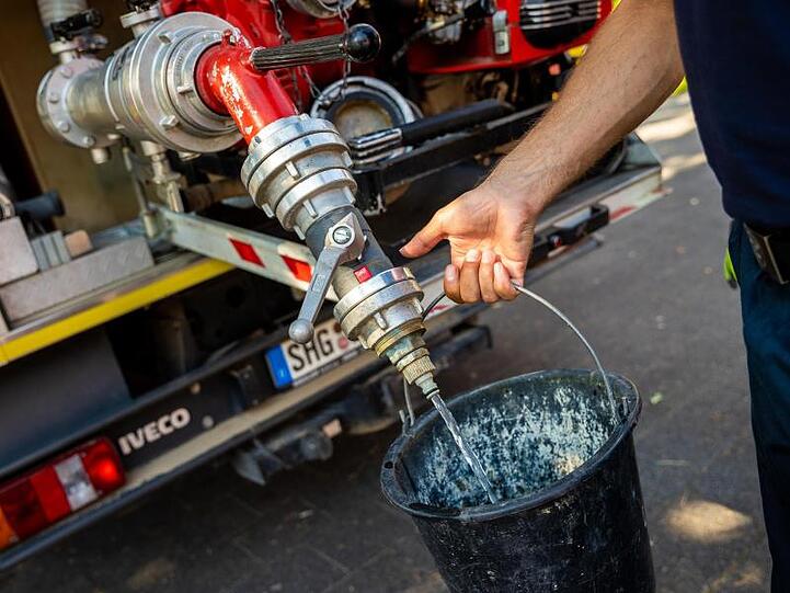Einsatzkräfte der Freiwilligen Feuerwehr Lauenau zapfen Löschwasser aus dem Tank eines ihrer Einsatzfahrzeuge.